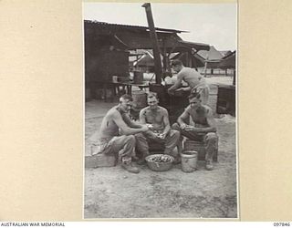 CAPE WOM, WEWAK AREA, NEW GUINEA. 1945-10-13. PRIVATE A. GRAHAM (1), PRIVATE J.P. GROGAN (2), AND PRIVATE A.A. DAVIS (3) PEELING POTATOES. THE UNIT COOK, PRIVATE C.A. BARKER (4), IS PLACING A TRAY ..