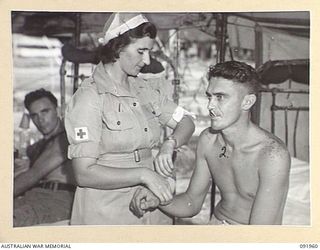 BOUGAINVILLE, 1945-04-18. PRIVATE E.M. HEWETT, AUSTRALIAN ARMY MEDICAL WOMEN'S SERVICE (1), TAKING THE TEMPERATURE OF WARRANT OFFICER L. HOLLOWAY (2), AT 2/1 GENERAL HOSPITAL