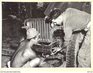 A SKILLED JAPANESE MECHANIC REPAIRING A JEEP AT 11 DIVISION SIGNALS. HE IS WORKING UNDER THE SUPERVISION OF SIGNALMAN G. COLVEAS