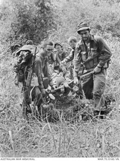 PHUOC TUY PROVINCE, SOUTH VIETNAM. 9 MARCH 1970. MEN FROM B COMPANY, 7TH BATTALION, THE ROYAL AUSTRALIAN REGIMENT (7RAR), CARRY A MATE WHO HAS COLLAPSED FROM HEAT EXHAUSTION TO A WAITING ..