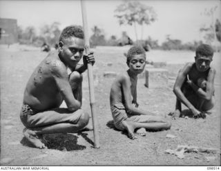 NAMATANAI, NEW IRELAND. 1945-10-29. THREE EMACIATED NATIVES WHO ALMOST STARVED DURING THE JAPANESE OCCUPATION, AWAIT TREATMENT AT THE AUSTRALIAN NEW GUINEA ADMINISTRATIVE UNIT NATIVE HOSPITAL. AN ..