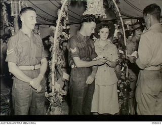 Torokina, Bougainville. 1945-08-15. VX73937 Corporal J.H. Rickard places a ring on the finger of his bride TFX13371 Private E.M. Townsend during their wedding ceremony at the 2/1st Australian ..