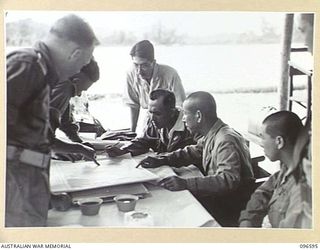 BONIS PENINSULA, BOUGAINVILLE. 1945-09-14. JAPANESE NAVAL COMMANDER TAKAHASHI INDICATING ON AN AUSTRALIAN MAP THE JAPANESE POSITIONS IN THE BUKA AREA TO MEMBERS OF AN AUSTRALIAN SURRENDER PARTY ..