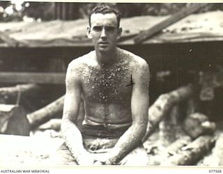 NX166426 LANCE-CORPORAL G.D. DEW, NO. 5 PLATOON (PIONEERS), HEADQUARTERS COMPANY, 27TH INFANTRY BATTALION AFTER WORKING IN THE UNIT SAWMILL WITH SAWDUST AND SMALL WOOD SHAVINGS STUCK TO HIS SWEAT ..