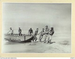 TAGESSI, BOUGAINVILLE ISLAND. 1945-01-17. PERSONNEL OF THE 7TH FIELD AMBULANCE DRAGGING ONE OF THE UNIT BOATS UP THE BEACH