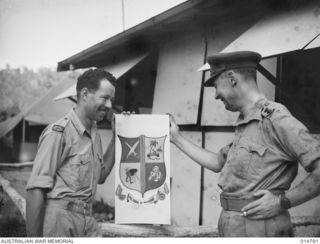 1943-05-05. NEW GUINEA. WAR CORRESPONDENTS' COAT OF ARMS. DENNIS ADAMS, ONE OF THE OFFICIAL WAR ARTISTS, PAINTED THIS COAT OF ARMS, DESIGNED BY WAR CORRESPONDENTS IN NEW GUINEA, TO HANG IN THEIR ..
