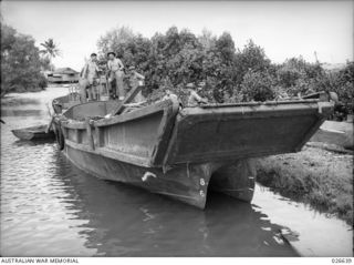 MILNE BAY, PAPUA. 1942-09. ONE OF THE JAPANESE INVASION BARGES USED IN THEIR ABORTIVE LANDING ATTEMPT AT MILNE BAY, NOW SALVAGED AND PUT INTO USE BY AUSTRALIAN ENGINEERS