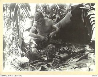 BOUGAINVILLE ISLAND. 1945-02-12. Q16823 PRIVATE A. TIMM, "C" COMPANY, 9TH INFANTRY BATTALION CLEANING HIS 2" MORTAR OUTSIDE HIS SHELTER WHICH HE HAS COVERED WITH BANANA LEAVES