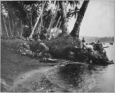 Landing operations on Rendova Island, Solomon Islands, 30 June 1943. Attacking at the break of day in a heavy rainstorm, the first Americans ashore huddle behind tree trunks and any other cover they can find.