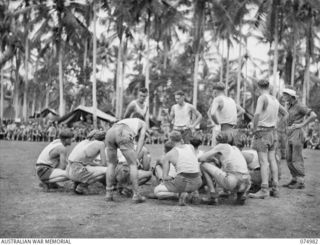 NAGADA, NEW GUINEA. 1944-07-26. THE CAPTAIN OF THE AUSTRALIAN RULES FOOTBALL TEAM OF THE 29/46TH INFANTRY BATTALION TALKING TO HIS MEN AT HALFTIME DURING THEIR MATCH AGAINST A TEAM FROM THE 37/52ND ..