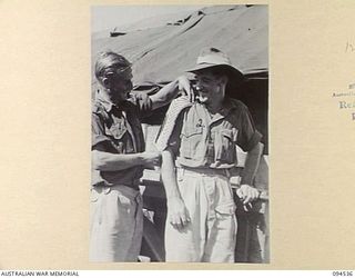 CAPE WOM, WEWAK, NEW GUINEA, 1945-07-31. PRIVATE H.R.W. SEATON (1) ADMIRING STRIPES ON PRIVATE M.T. WATERFIELD (2), BOTH OF CANTEEN BULK STORES AND ISSUING POINT, OPERATED BY THE AUSTRALIAN ARMY ..