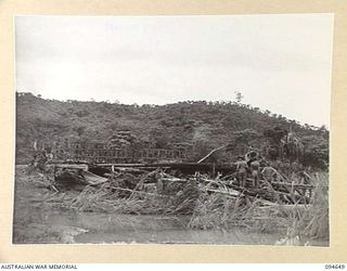 TOL, NEW BRITAIN, 1945-08-01. HUGE LOGS JAMMED UNDER THE APPROACHES OF AN OLD BRIDGE OVER THE WULWUT RIVER IN 4 FIELD COMPANY, ROYAL AUSTRALIAN ENGINEERS, AREA. THE FORCE OF THE DEBRIS CARRIED THE ..