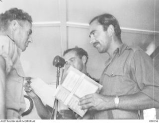 WEWAK POINT, NEW GUINEA. 1945-10-23. SERGEANT N. BRAY (3) ASKING PRIVATE L. HARMES, 19 BRIGADE (1) A QUESTION, WHILE SERGEANT E. PARRANT (2) STANDS BY TO HEAR THE ANSWER. THE MEN ARE TAKING PART IN ..