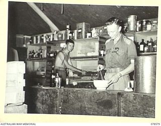 BOUGAINVILLE ISLAND. 1945-01-23. N235597 STAFF SERGEANT C.M. MORTAL (1) AND VX66123 LIEUTENANT J. WINTER (2) MIXING MEDICINES IN THE DISPENSARY OF THE 109TH CASUALTY CLEARING STATION