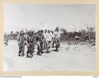 KAHILI, SOUTH BOUGAINVILLE. 1945-09-09. MAJOR F.C. TAYLOR, BUIN LIAISON GROUP, 2 CORPS, WALKING WITH THE JAPANESE REPRESENTATIVES, TO SELECT A CAMP SITE ON THE BEACH AT KAHILI AIRSTRIP