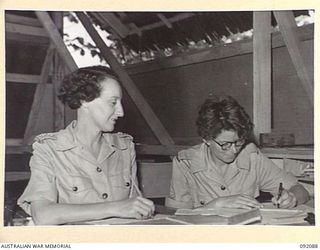 LAE, NEW GUINEA, 1945-05-21. LIEUTENANT K.M. SPROOLES, ADJUTANT (1), CHECKING PAY BOOKS WITH SERGEANT A. LAWSON (2), IN THE ORDERLY ROOM AT THE AUSTRALIAN WOMEN'S ARMY SERVICE BARRACKS IN BUTIBUM ..