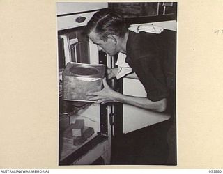 CAPE WOM, WEWAK AREA, NEW GUINEA, 1945-07-11. PRIVATE D. BLADON, FIELD DETACHMENT LAND HEADQUARTERS MEDICAL RESEARCH UNIT, PLACING PLASMA IN A REFRIGERATOR, WHERE IT WILL BE KEPT UNTIL THE WEEKLY ..