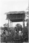 Men standing under raised house at feast