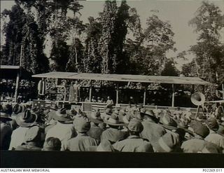 Torokina, Bougainville, 1945-08-15. A large crowd of Australian soldiers attends a memorial service, probably on a sports field, on Victory in the Pacific (VP) Day. The service is being conducted ..