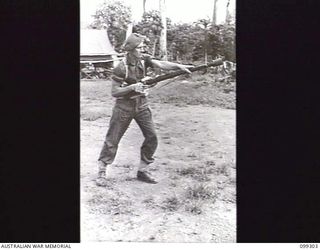 RABAUL, NEW BRITAIN, 1945-12-06. A SOLDIER ARMED WITH A GRENADE DISCHARGER CUP ATTACHED TO A .303 INCH RIFLE FIRES FROM THE HIP DURING A DEMONSTRATION OF VARIOUS INFANTRY WEAPONS. THIS POSITION IS ..