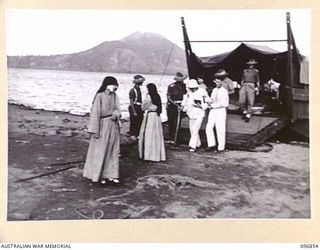 Father Gerard Peekel being assisted from a landing barge after being released by the Japanese during a surrender ceremony at Fangalawa Bay. Father Peekel along with five nuns, Sisters M Brigitta, M ..