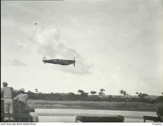 KIRIWINA, TROBRIAND ISLANDS, PAPUA. 1944-01-11. SPITFIRE AIRCRAFT OF NO. 79 SQUADRON RAAF SHOOTING UP THE RUNWAY DURING AN AEROBATIC DISPLAY. THIS SPITFIRE AIRCRAFT CLEAVES THE AIR WITH THE SPEED ..