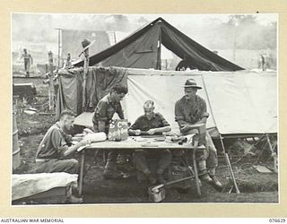 LAE, NEW GUINEA. 1944-10-27. THE OPEN AIR ORDERLY ROOM OF B COMPANY, 14/32ND INFANTRY BATTALION WITH THE STAFF AT WORK WHILE AWAITING EMBARKATION. IDENTIFIED PERSONNEL ARE:- VX74844 PRIVATE N.W. ..