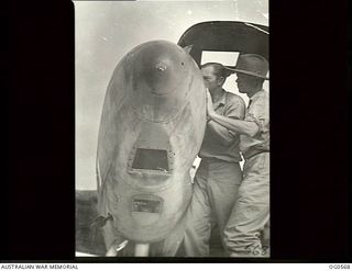 MILNE BAY, PAPUA. 1943-07-31. LEADING AIRCRAFTMAN H. HARDIE OF KOGARAH, NSW (LEFT) AND AN ASSISTANT FITTING A MAGAZINE ON A CAMERA LENS IN THE NOSE OF A P38 LOCKHEED LIGHTNING PHOTOGRAPHIC ..