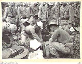 KAIRIRU ISLAND, NEW GUINEA. 1945-09-17. WARRANT OFFICER 2 D.W. TREADWELL, FIELD SECURITY SERVICE, HEADQUARTERS 6 DIVISION GOING THROUGH THE BELONGINGS OF JAPANESE NAVAL FORCES PRIOR TO THEIR ..