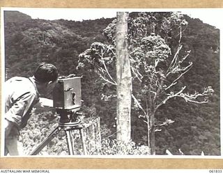 MR GEORGE HEATH, CHIEF CAMERAMAN OF CHAUVEL'S PRODUCTIONS, FILMING VISTAS FOR THE PRODUCTION, "RATS OF TOBRUK" FROM THE OWERS' CORNER SIGNAL STATION ON THE KOKODA TRAIL IN THE OWEN STANLEY RANGES ..