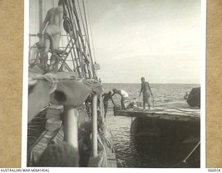 BUNA, NEW GUINEA. 1944-06-14/02. A LARGE RAFT WITH A JEEP ABOARD BEING SECURED TO A VESSEL OF THE 12TH WATER TRANSPORT OPERATING COMPANY FOR A TOW TO LAE