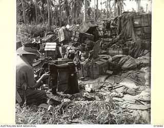 ALEXISHAFEN AREA, NEW GUINEA. 1944-04-27. A MEMBER OF THE 8TH INFANTRY BRIGADE EXAMINES A JAPANESE HEAVY DUTY SEWING MACHINE AMONG ABANDONED ENEMY EQUIPMENT AT NORTH ALEXISHAFEN