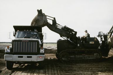 Navy Seabees from Navy Mobile Construction Battalion Four (NMCB-4) use a caterpillar bulldozer to dump earth into a dump truck. The Seabees are assigned to Naval Facilities Guam and they are making preparation for personnel and equipment due to the relinquishing of Subic Bay Naval Station. EXACT DATE SHOT UNKNOWN