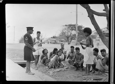 Group of unidentified locals sitting under a tree on the street having conversation, Port Moresby, Papua New Guinea