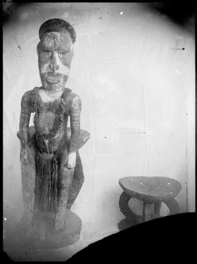 Carved figure beside low carved stool, Rabaul, New Guinea, ca. 1929 / Sarah Chinnery