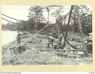 LAE, NEW GUINEA. 1944-08-08. TRUCKS PULLING THE "FLYING FOX" CARRIAGE BACK ACROSS THE BUSU RIVER DURING THE BUILDING OF A PERMANENT BRIDGE BY TROOPS OF THE 30TH FIELD COMPANY. IDENTIFIED PERSONNEL ..