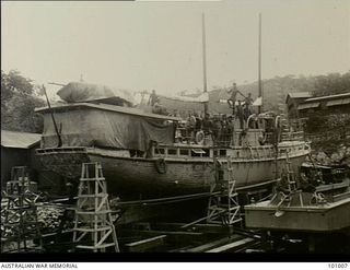 Port Moresby, Papua. 1944-08-25. Some natives standing on Stradbroke 2, a 4th Sea Ambulance transport ship, on the slips at Napa Napa No. 2 Watercraft workshops undergoing repairs after her ..