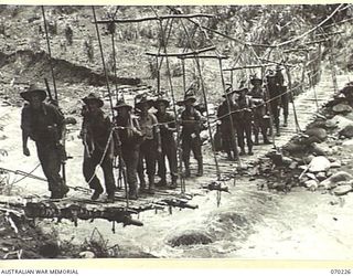 FARIA VALLEY, NEW GUINEA. 1944-02-10. PERSONNEL OF THE 11TH FIELD BATTERY, 4TH FIELD REGIMENT, ON A ROPE SUSPENSION BRIDGE CROSSING THE FARIA RIVER NEAR GUY'S POST IN THEIR MOVE TO FORWARD ..