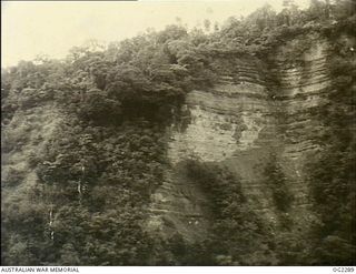 NORTH EAST NEW GUINEA. 1945-03-09. NOT ONLY DO AIRMEN AND GROUND FORCES HAVE TO CONTEND WITH THIS TYPE OF RUGGED JUNGLE COUNTRY BUT THEY ALSO HAVE TO FACE SHEER ROCK-FACED CLIFFS LIKE THOSE SHOWN ..