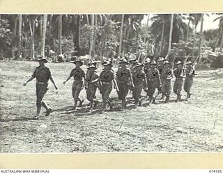 SIAR, NEW GUINEA. 1944-06-22. PERSONNEL OF NO.2 PLATOON, HEADQUARTERS COMPANY, 57/60TH INFANTRY BATTALION MOVING ACROSS THE UNIT PARADE GROUND AT THE CONCLUSION OF THE MORNING PARADE. IDENTIFIED ..