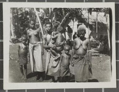 Three women and three children outside a hut at Nissan