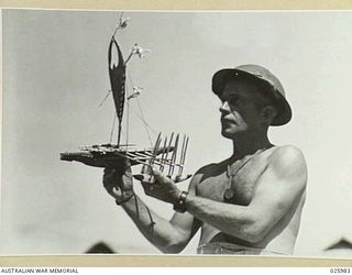 PORT MORESBY, PAPUA. 1942-07-20. AN AUSTRALIAN SOLDIER ADMIRES HIS SOUVENIR OF NEW GUINEA, A MODEL LAKATOI, OR NATIVE SAILING CRAFT