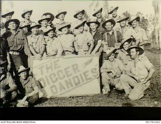 Lae, New Guinea. 1944-09-07. Group portrait of members of `The Digger Dandies' concert party, Queensland Lines of Communication Area, grouped around a sign bearing their name. The entertainers are ..