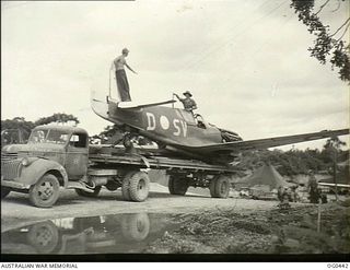 KIRIWINA, TROBRIAND ISLANDS, PAPUA. 1943-12-26. A KITTYHAWK FIGHTER AIRCRAFT, CODED SV-D, OF NO. 76 SQUADRON RAAF DAMAGED IN A LANDING BEING HAULED ON THE BACK OF A TRUCK INTO NO. 26 REPAIR AND ..