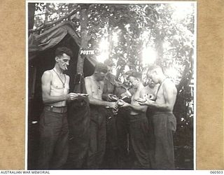 FINSCHHAFEN AREA, NEW GUINEA. 1943-11-13. QX17268 CORPORAL A. A. CURTIS, POSTAL ORDERLY AT HEADQUARTERS, 9TH AUSTRALIAN DIVISION HANDLING OUT MAIL TO TROOPS OF THE HEADQUARTERS STAFF