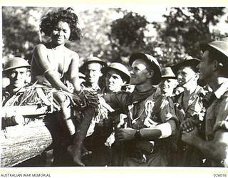 PAPUA, NEW GUINEA. 1942-07. MEMBERS OF AN AUSTRALIAN INFANTRY PATROL STOP IN A COASTAL VILLAGE TO MAKE THE ACQUAINTANCE OF A DUSKY "KIKINI" WHICH IS THE PAPUAN TRANSLATION OF A YOUNG GIRL