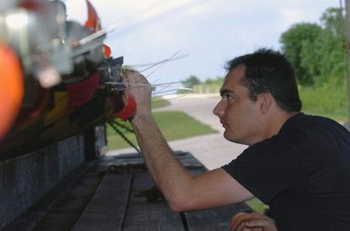 US Air Force (USAF) STAFF Sergeant (SSGT) Larry Cartwright, Munitions Specialists, 5th Bomb Wing (BW), inspect the arming wires on M-117 750-pound general-purpose bombs, mounted atop a munitions trailer, at Andersen Air Force Base (AFB), Guam