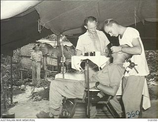 NEW GUINEA. C. 1944-05. RAAF DENTIST ATTENDING TO A PATIENT IN A DENTAL SECTION