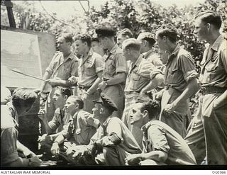 AIRCREW OF NO. 22 (BOSTON) SQUADRON RAAF, BEING BRIEFED. STANDING, LEFT TO RIGHT: FLIGHT LIEUTENANT (FLT LT) E. J. O'DRISCOLL, STAWELL, VIC;408648 PILOT OFFICER (PO) TERRANCE JOHN GAWNE, SURREY ..