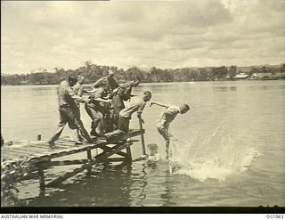 MADANG, NEW GUINEA. C. 1944-12. CHRISTMAS SPIRIT WAS IN EVIDENCE AT RAAF MEDICAL RECEIVING STATION. NURSES AND RAAF MEMBERS BEING TOSSED FROM A JETTY INTO THE HARBOUR